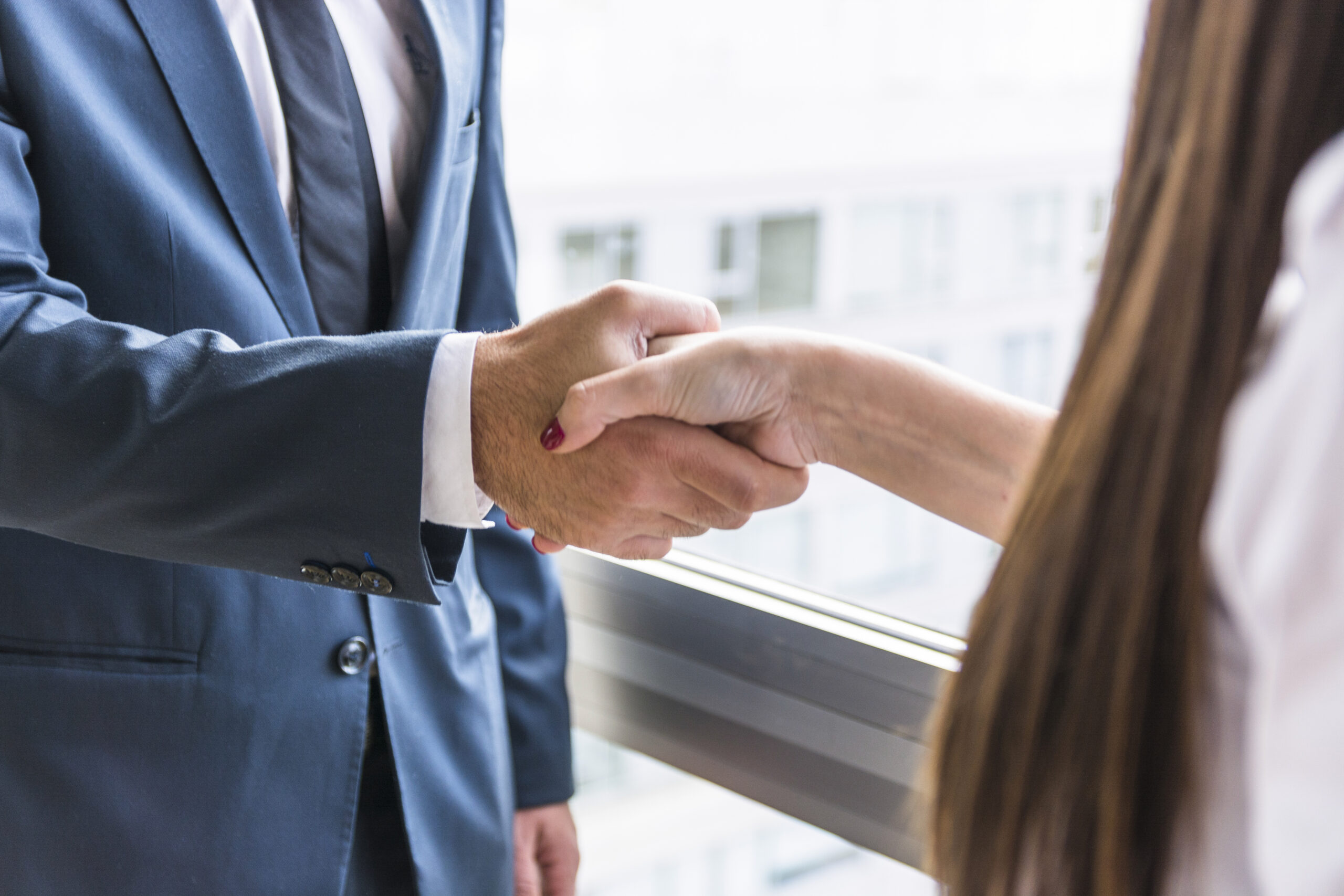 close-up-businesswoman-businessman-shaking-hands-scaled.jpg